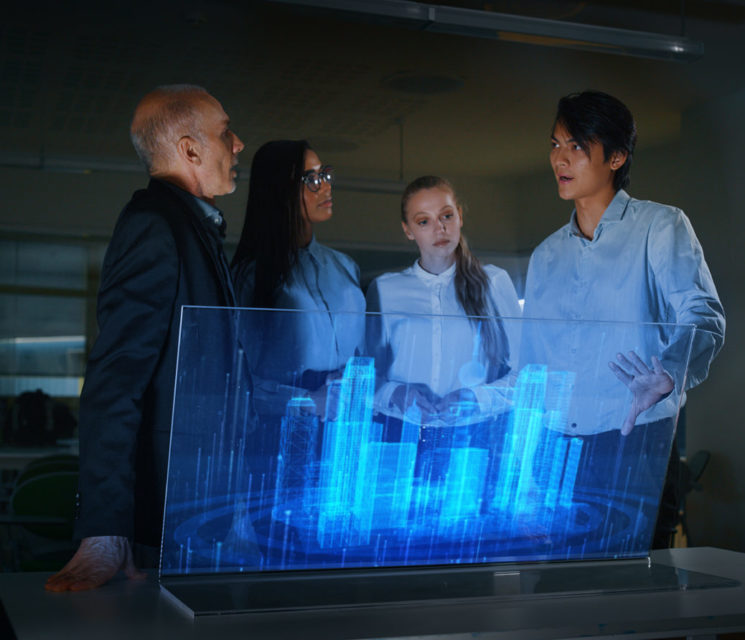 A group of modern designers are using a futuristic sophisticated technology screen with augmented reality holograms for a new project realization in an office.